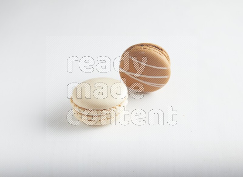 45º Shot of of two assorted Brown Irish Cream, and White Caramel fleur de sel macarons on white background