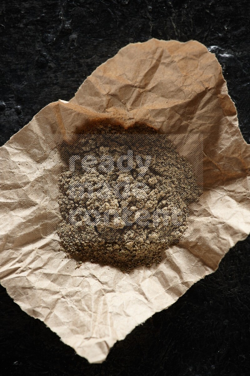 بودرة الهيل في قطعة من الورق على خلفية سوداء