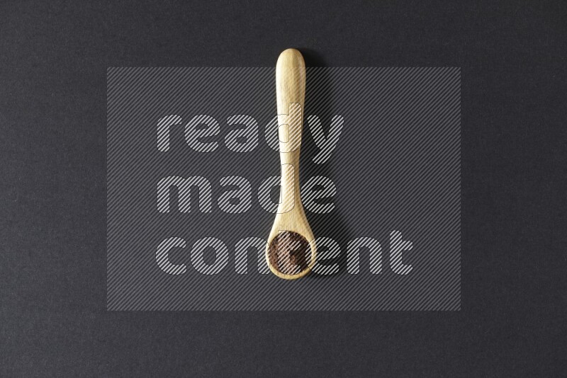 بودرة القرنفل في ملعقة خشبية علي خلفية سوداء