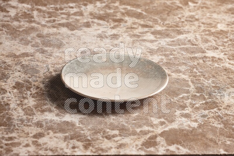 A multicolored pottery plate on beige marble background