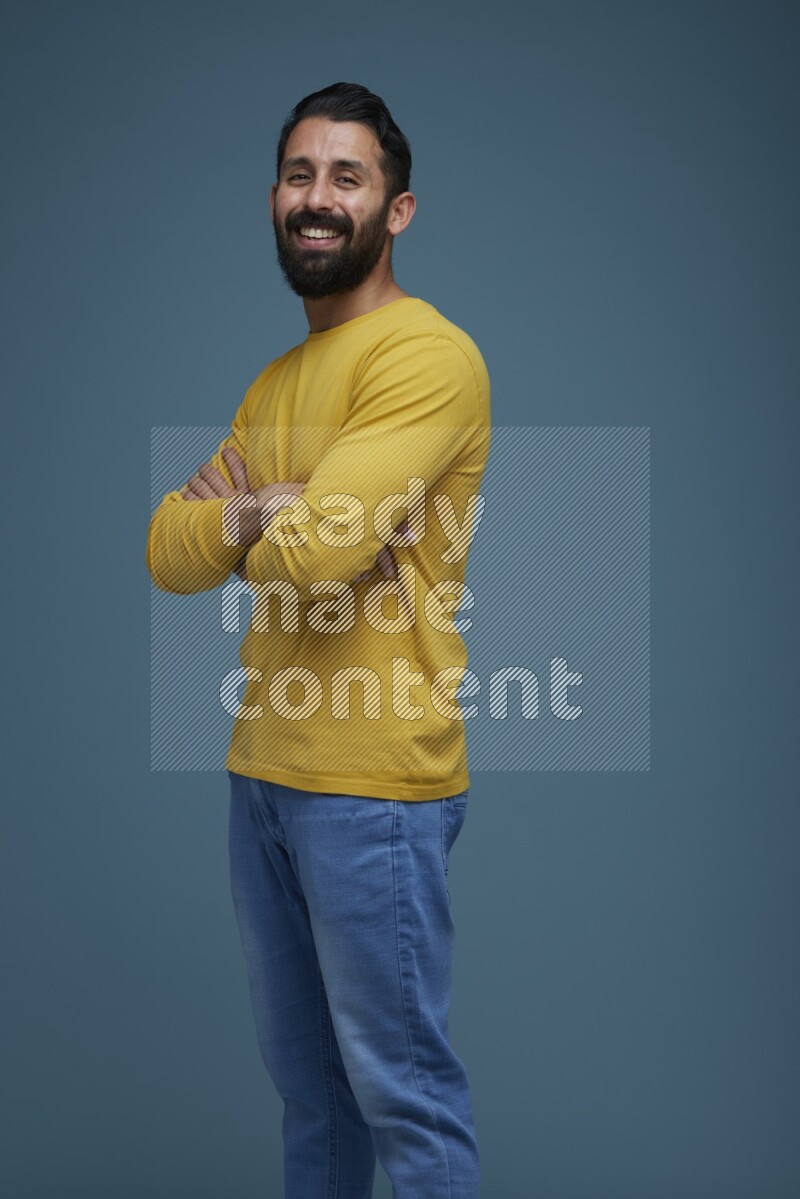Man posing in a blue background wearing a yellow shirt