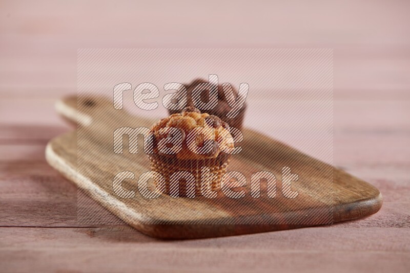 Vanilla mini cupcake topped with chocolate chips on a wooden board