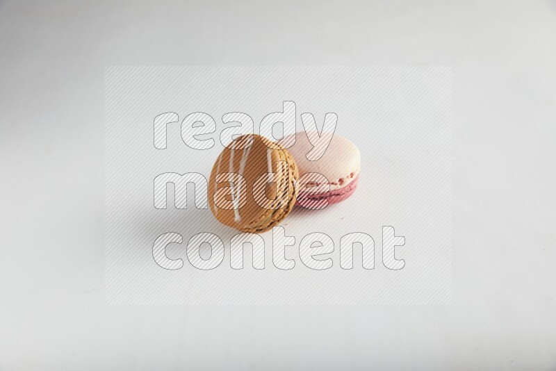 45º Shot of of two assorted Brown Irish Cream, and Pink Litchi Raspberry macarons on white background