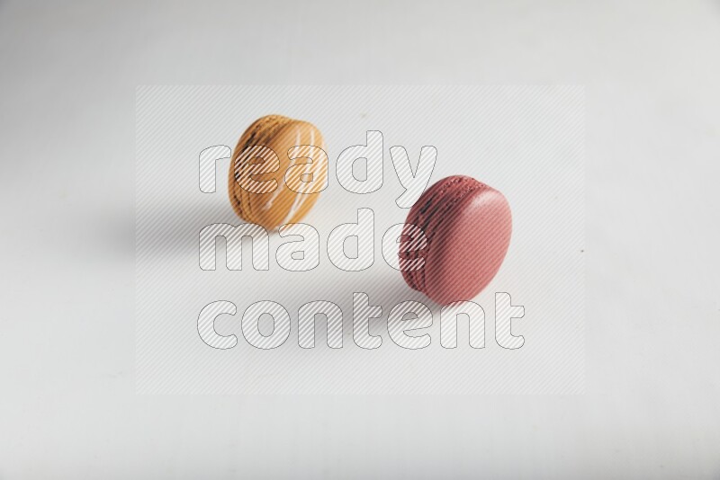 45º Shot of of two assorted Brown Irish Cream, and Red Velvet macarons on white background