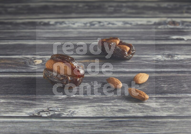 two almond stuffed madjoul dates on a wooden grey background