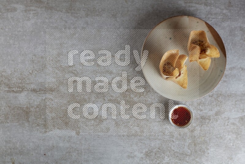 wonton cups with soy sauce ramkin on multi colored pottery on grey textured counter top