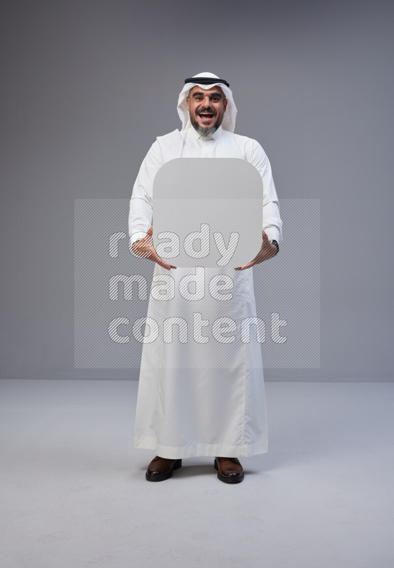Saudi man Wearing Thob and white Shomag standing holding social media sign on Gray background