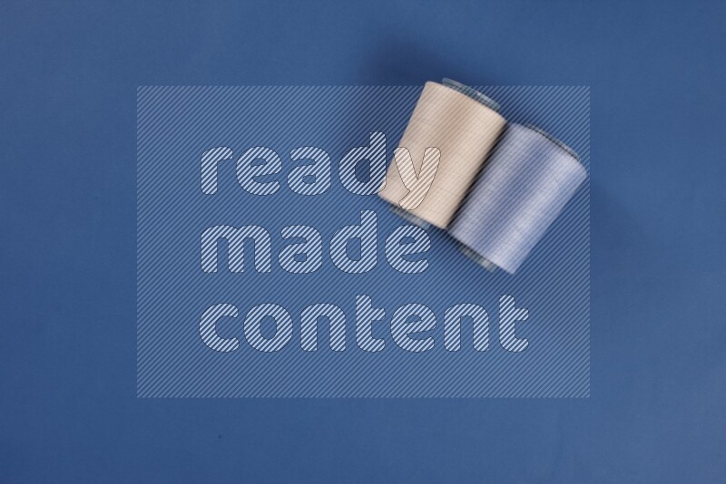 مجموعة من أدوات الخياطة والتفصيل بيضاء اللون على خلفية زرقاء