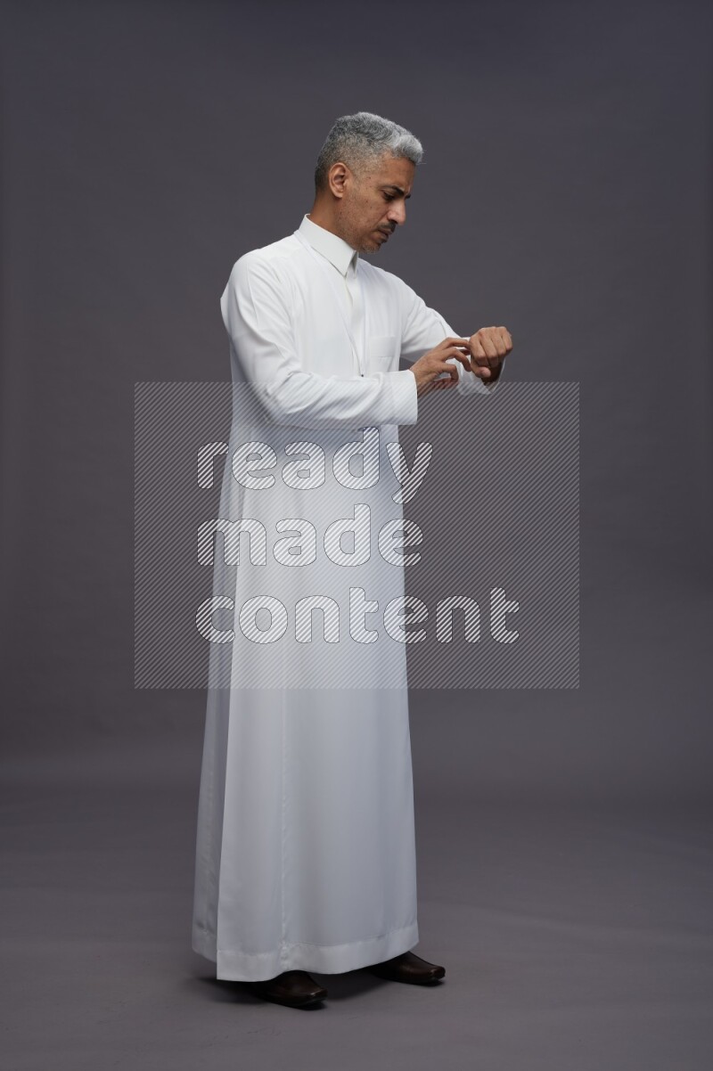 Saudi man wearing thob with neck strap employee badge standing interacting with the camera on gray background