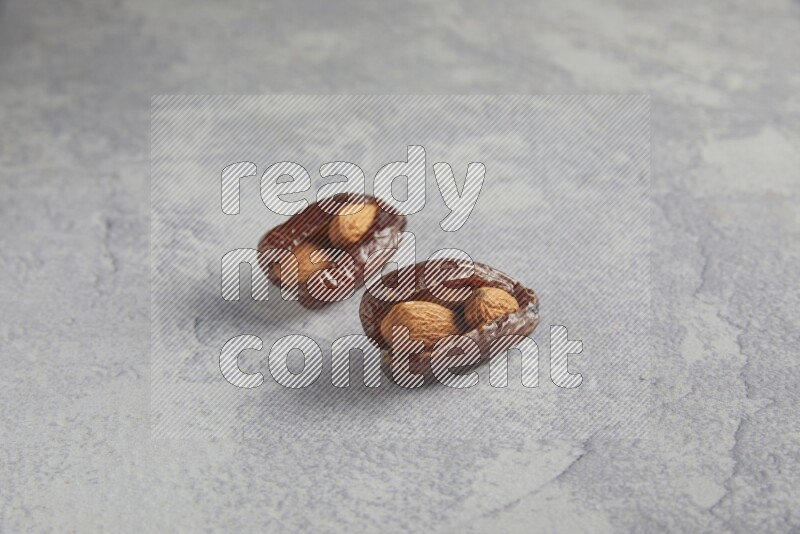 Two Almond stuffed date on a light grey background