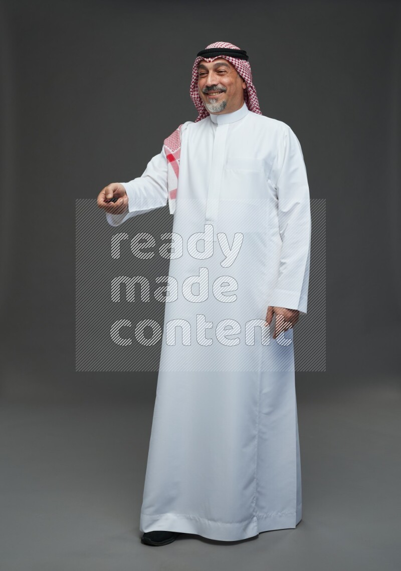 Saudi man with shomag Standing holding car key on gray background