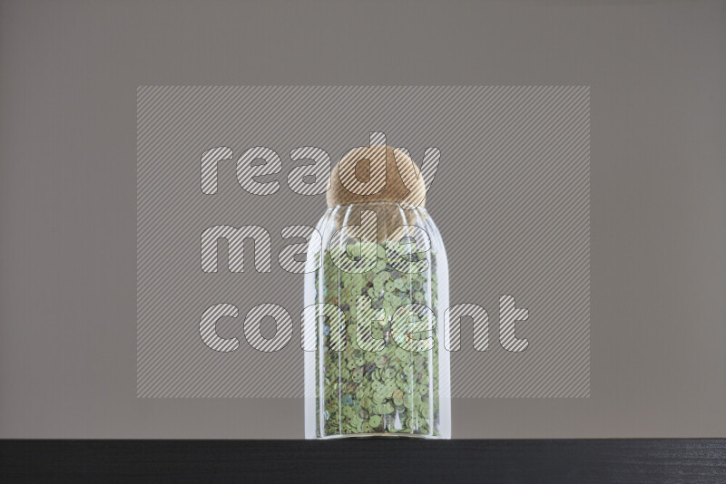 Sequins in a glass jar on black background