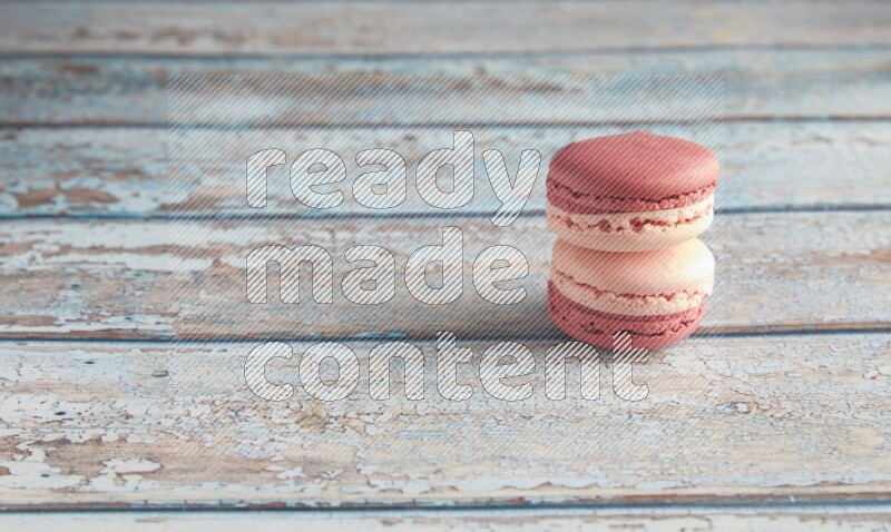 45º Shot of two Pink Litchi Raspberry macarons on light blue wooden background