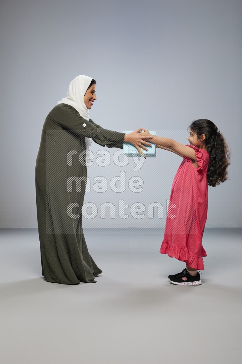A girl giving a gift to her mother on gray background