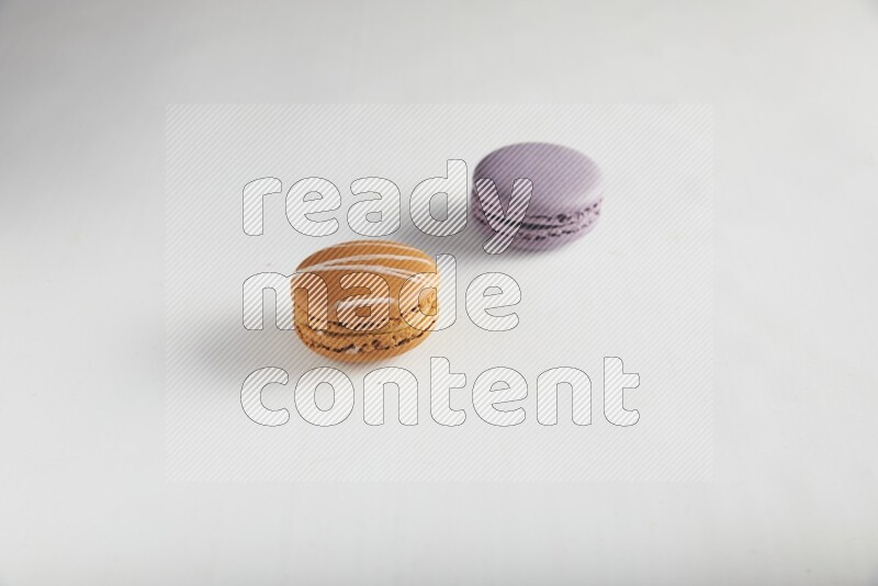 45º Shot of of two assorted Brown Irish Cream, and Purple Blueberry macarons on white background