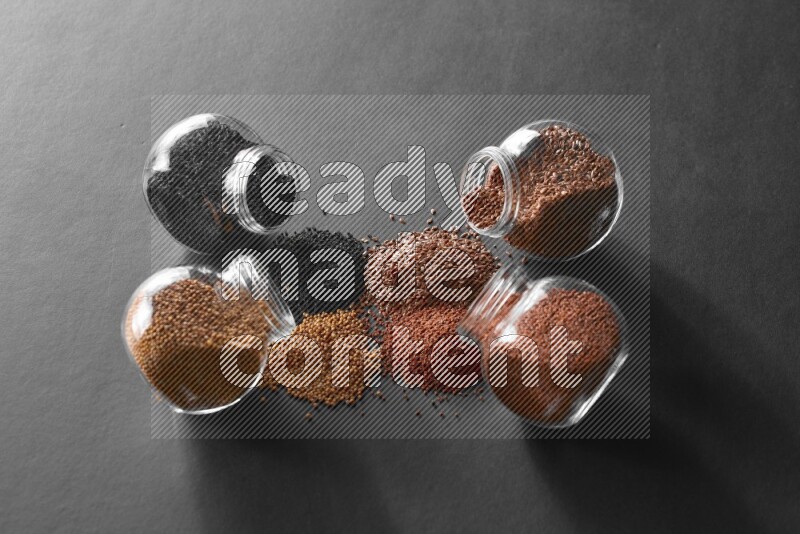 حبة البركة و حبوب الخردل وحبوب الكتان وحب الرشاد في أوعية زجاجية علي خلفية سوداء