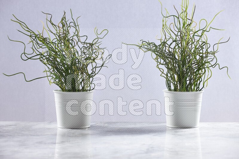 Two green artificial plants in white pot on grey marble background