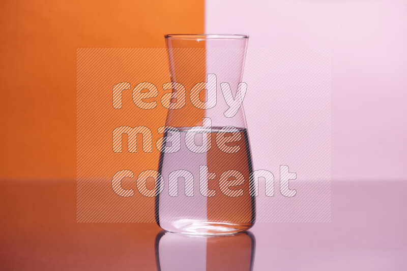 The image features a clear glassware filled with water, set against orange and rose background