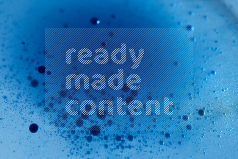 لقطات مقربة لقطرات ألوان مائية زرقاء على سطح الزيت على خلفية زرقاء