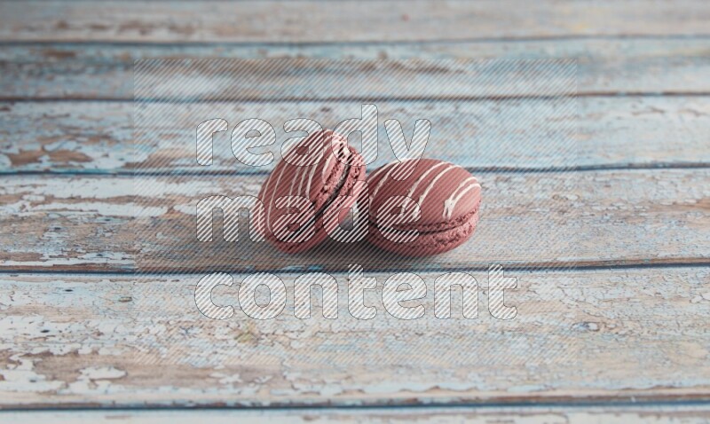 45º Shot of two Red Poppy Flower macarons on light blue wooden background