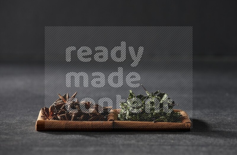 2 squares of cinnamon sticks full of star anise and dried mint leaves on black flooring