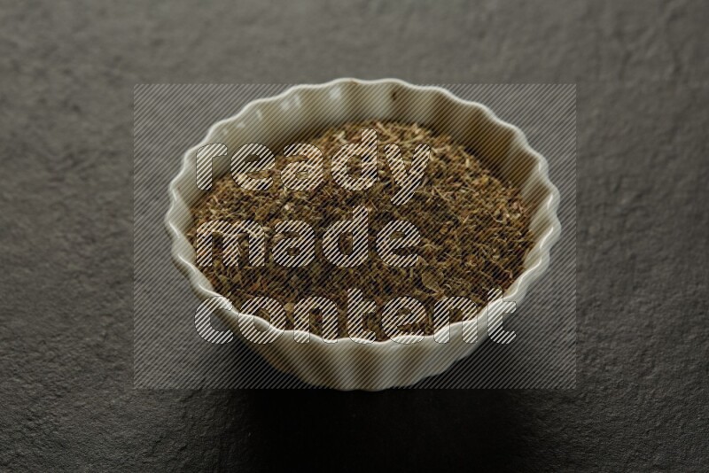 wooden round sauce bowl filled with herbs on grey textured countertop