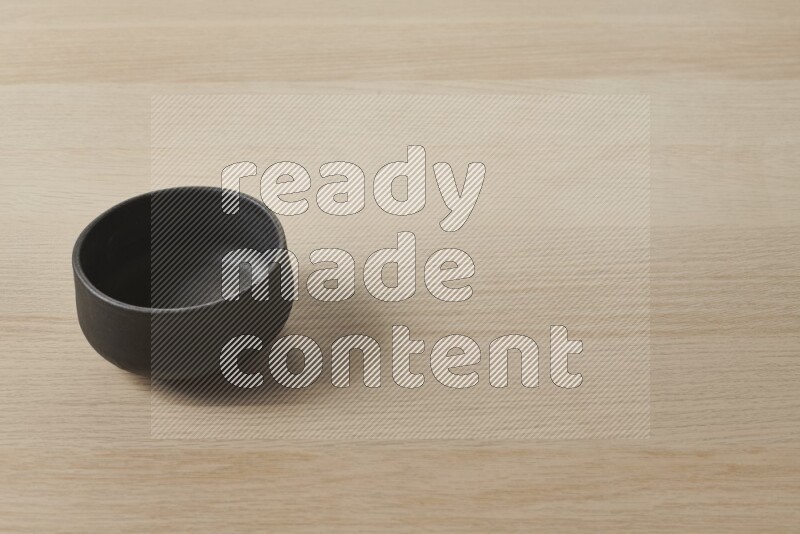 A black pottery bowl on light wooden background