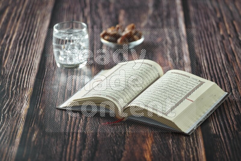 Quran with dates, prayer beads and different drinks all placed on wooden background