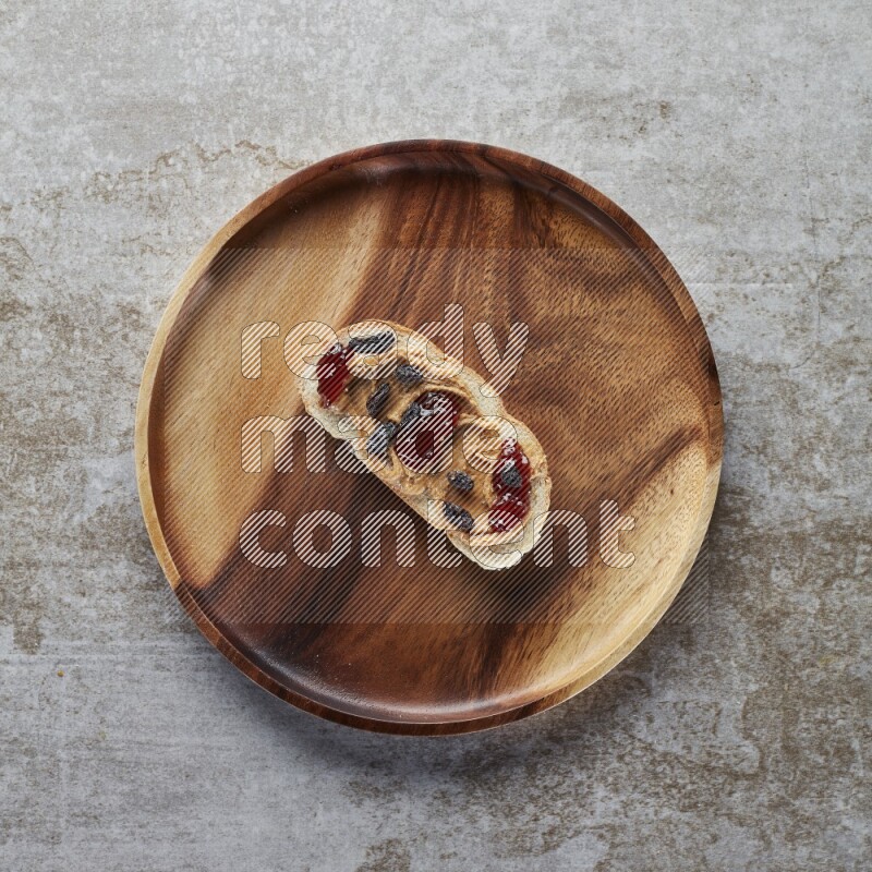 open faced peanut butter sandwich with jam and dried cranberries on a grey textured background