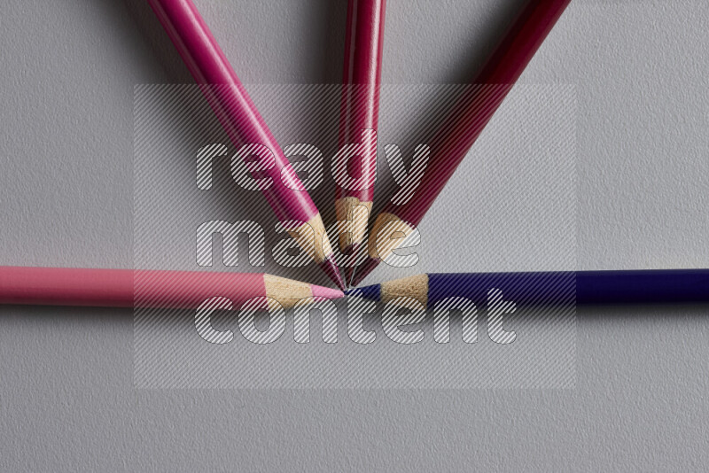 An arrangement of colored pencils in different colors on grey background