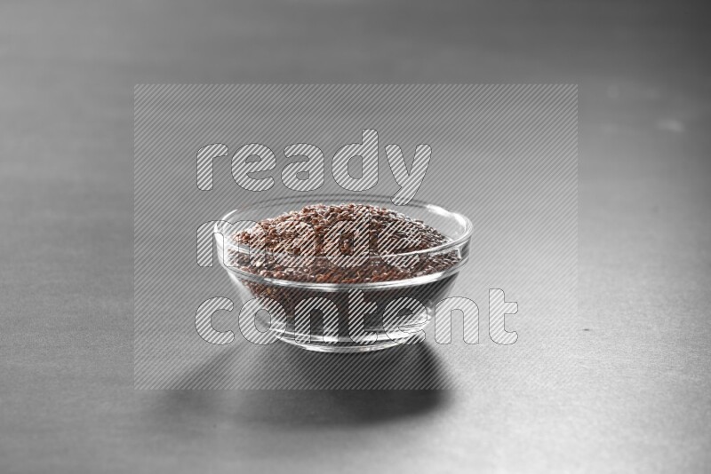 A glass bowl full of flax on black flooring