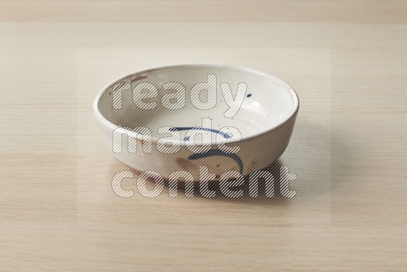 A multicolored pottery bowl on light wooden background