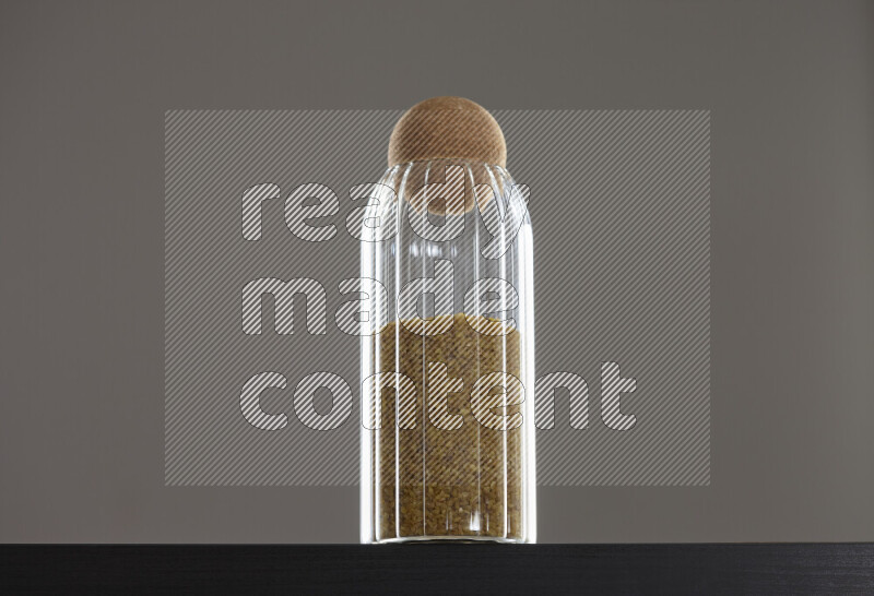 Coarse bulgur in a glass jar on black background