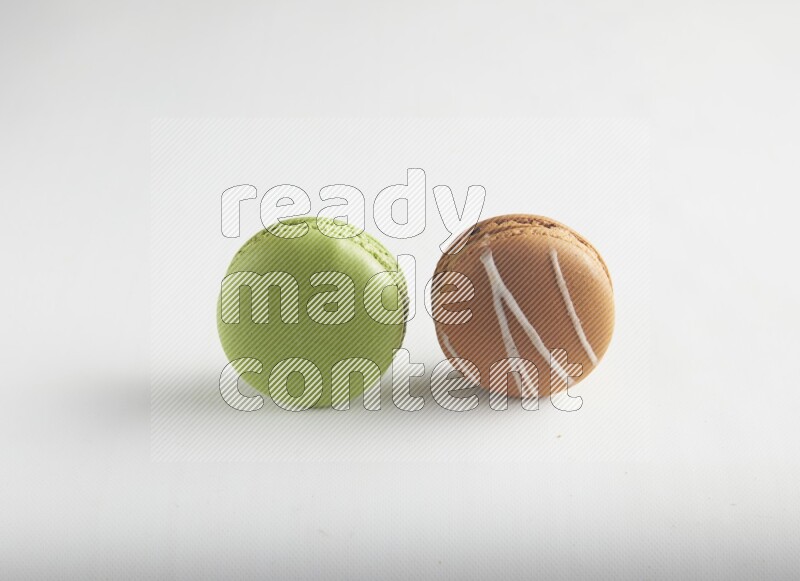 45º Shot of of two assorted Brown Irish Cream, and Green Pistachio macarons on white background