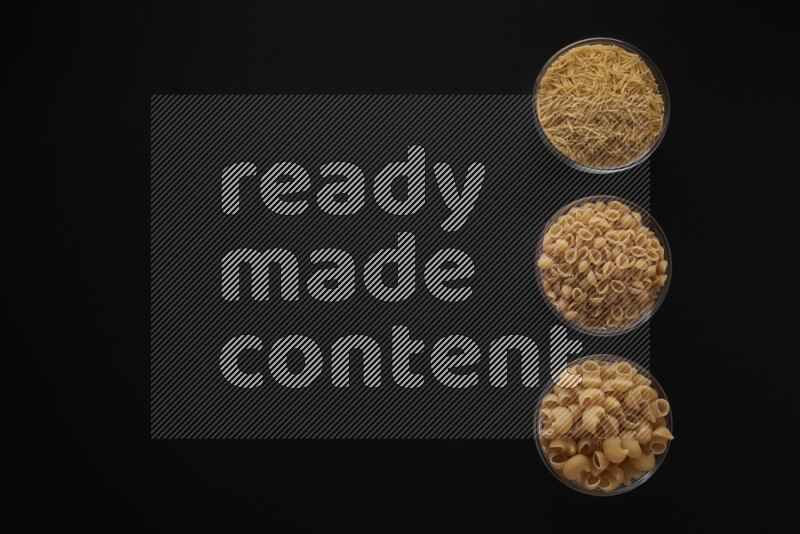 Different pasta types in 3 glass bowls on black background