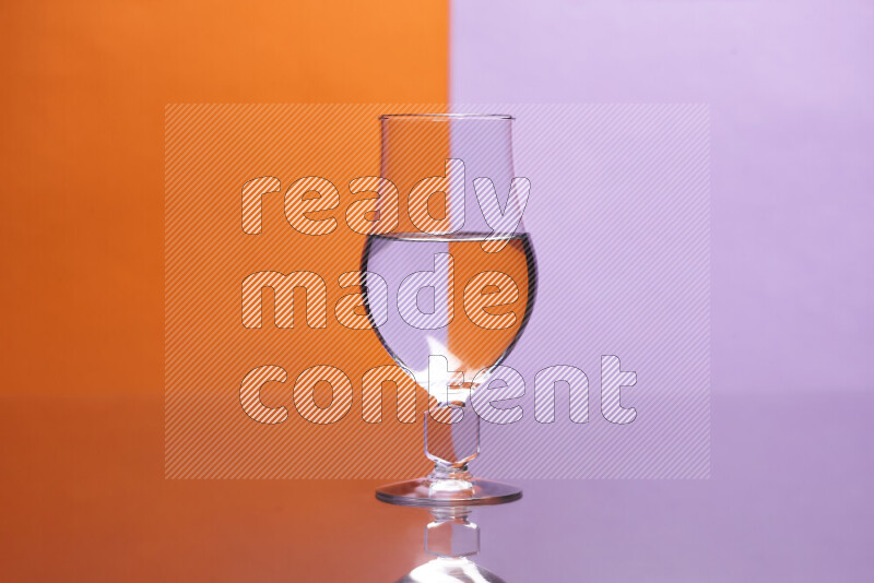 The image features a clear glassware filled with water, set against orange and light purple background