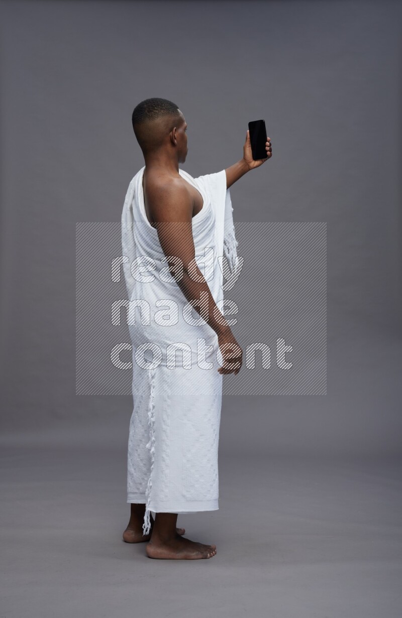 A man wearing Ehram Standing taking selfie on gray background