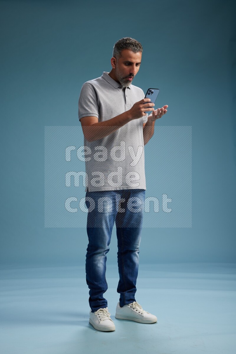 Man Standing texting on phone on blue background