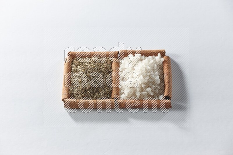 2 squares of cinnamon sticks full of white salt and cumin on white flooring