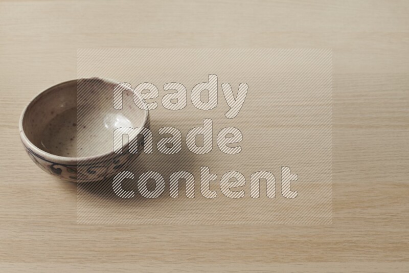 A multicolored pottery bowl on light wooden background