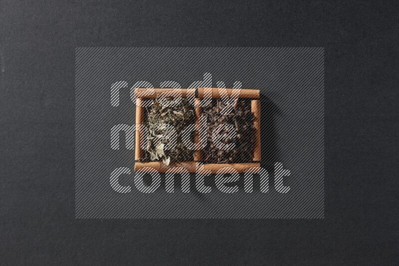 2 squares of cinnamon sticks full of cloves and dried basil on black flooring