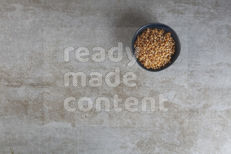 corn kernel in a black ceramic bowl on a grey textured countertop