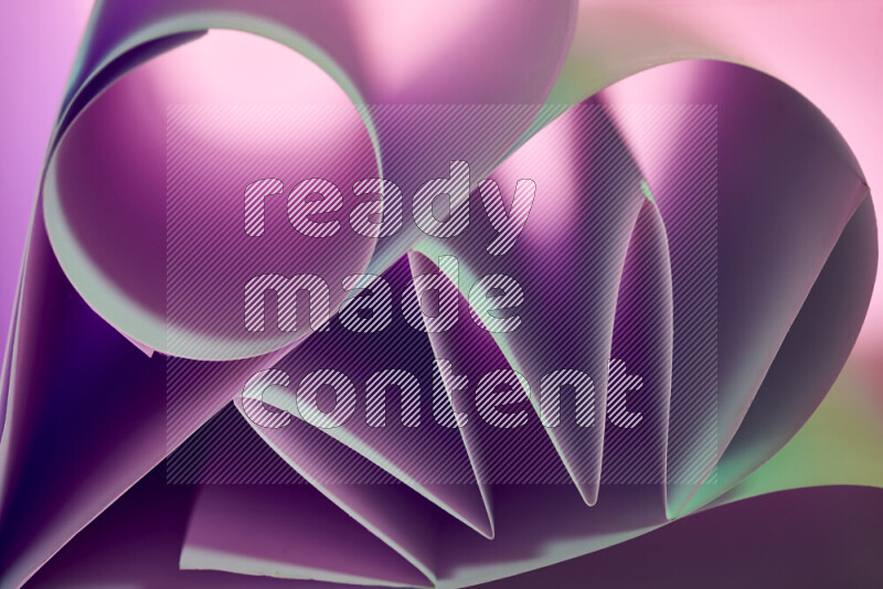 An artistic display of paper folds creating a harmonious blend of geometric shapes, highlighted by soft lighting in green and purple tones