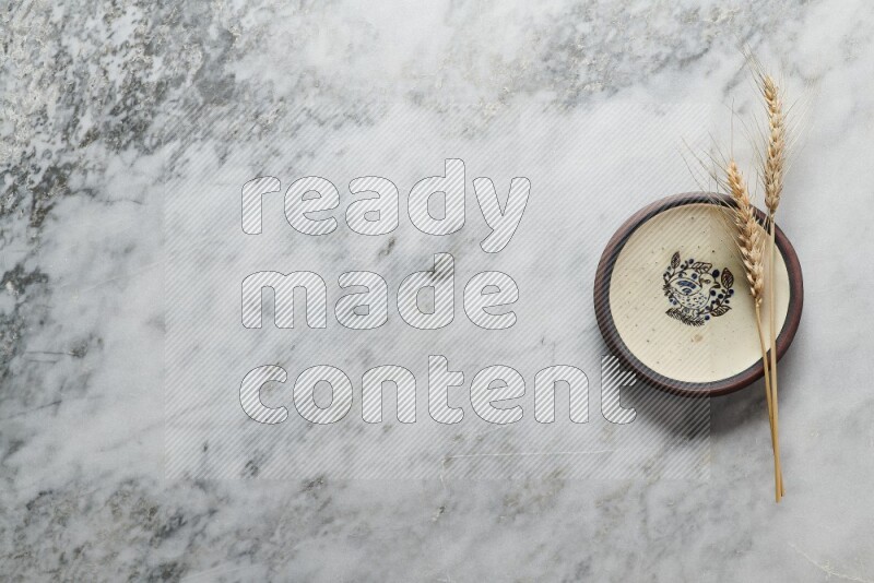 Wheat stalks on decorative pottery plate on grey marble background
