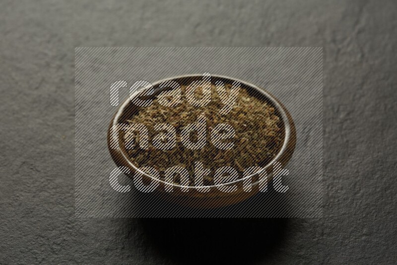 multi color round sauce bowl filled with herbs on grey textured countertop