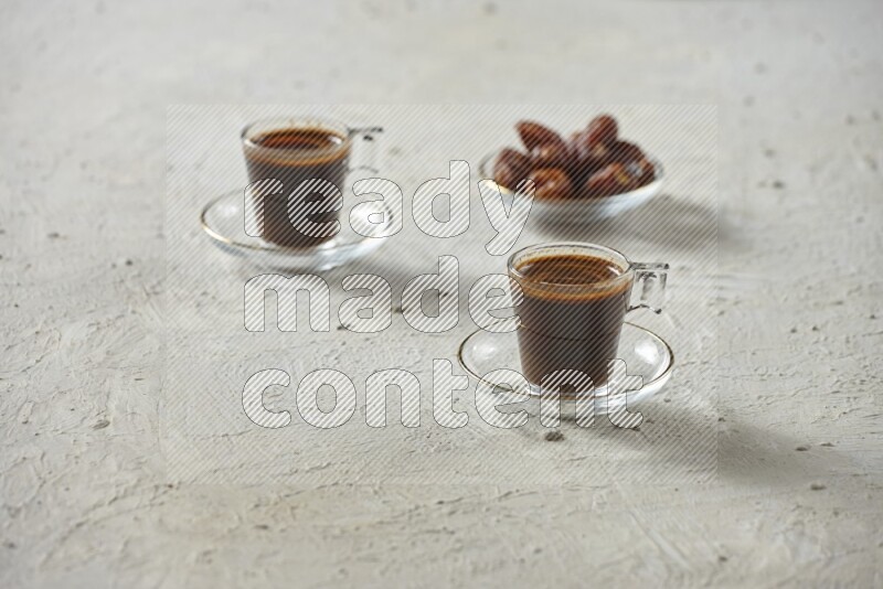 A coffee glass cup with dates and tea on textured white background