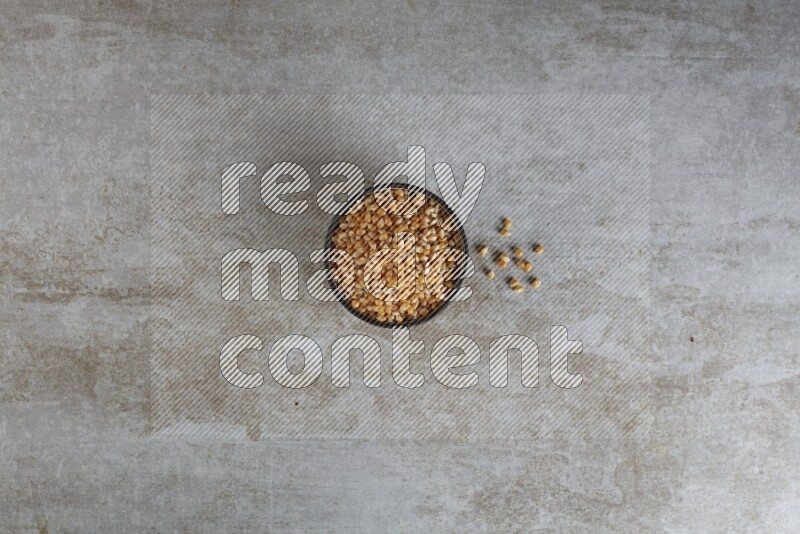 corn kernel in multi-colored pottery bowl on a grey textured countertop