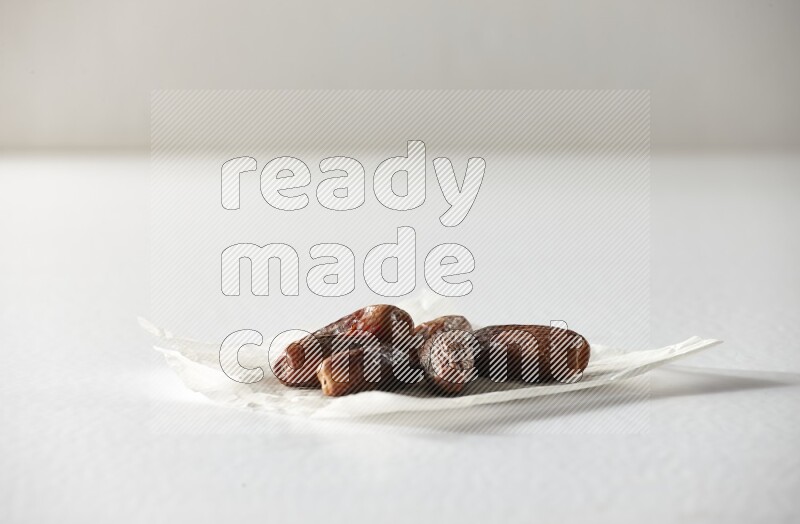 Dried dates on a crumpled piece of paper on a white background in different angles