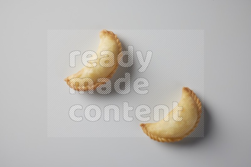 Two fried sambosa from a top angle on a white background