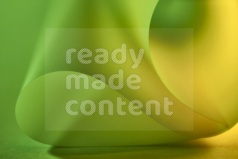 An abstract art piece displaying smooth curves in green and yellow gradients created by colored light